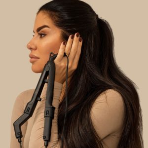 Žena sa dugom tamnom kosom drži aparat za keratinsku nadogradnju kose